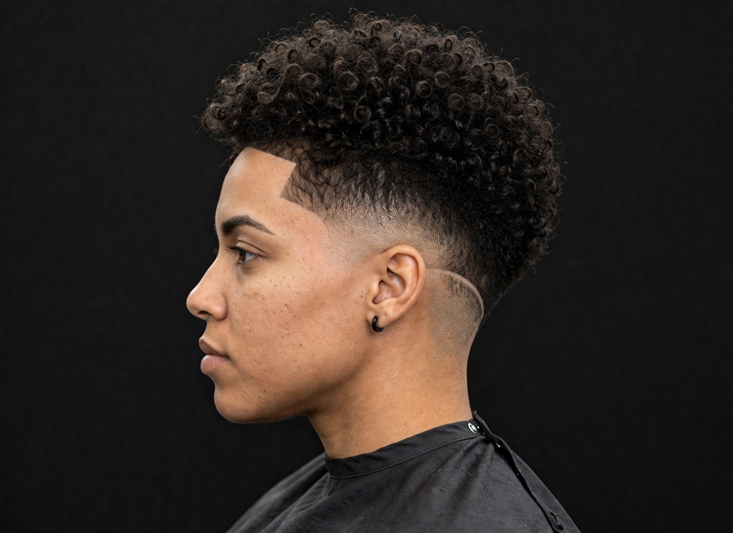Rounded Curl Top With Burst Fade And Etched Arc — side profile barber reference photo showing the fade line and top shape
